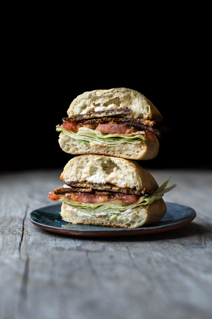 Tofu bacon BLT sandwich cut in half on a place