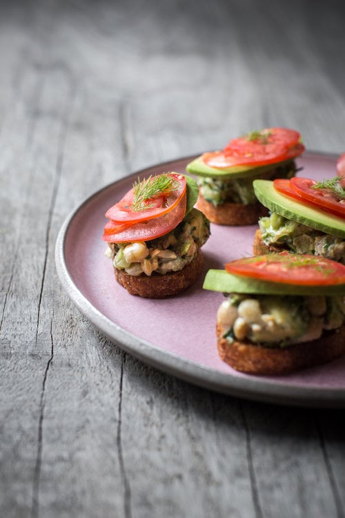 Chickpea avocado salad on sliced baguette with tomatoes