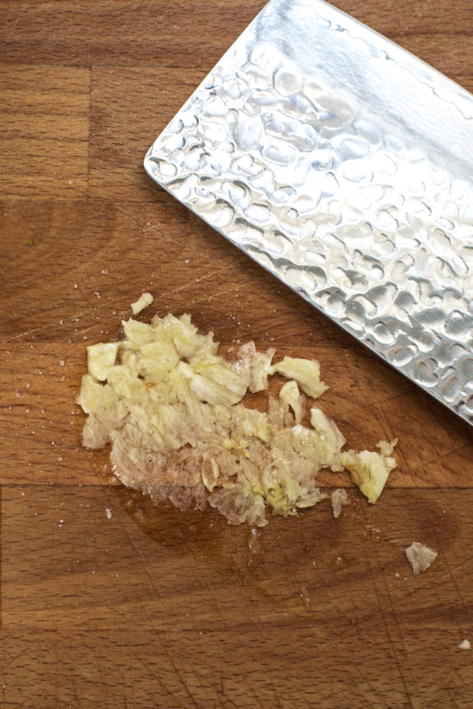 Smashed garlic on a wooden cutting board