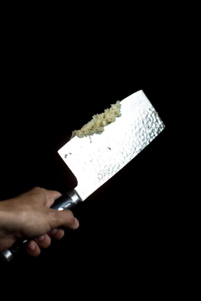 Knife with smashed and chopped garlic on it