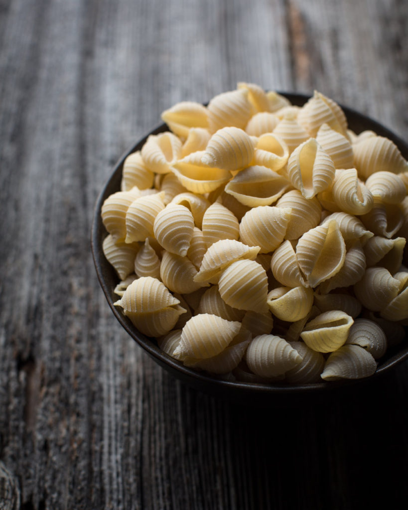 bowl of uncooked macaroni shells.