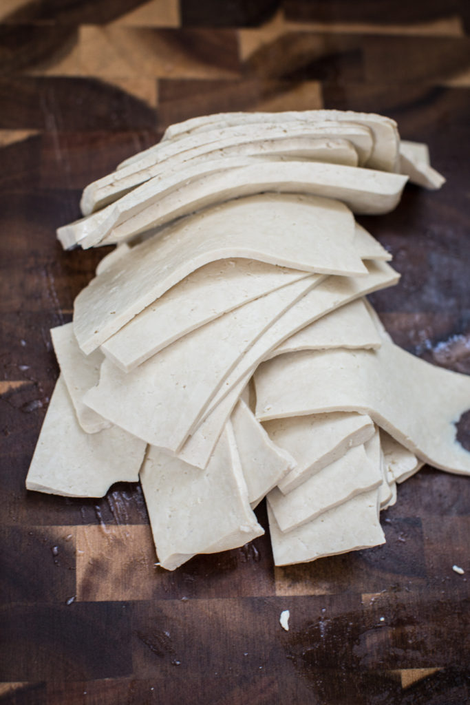 Thinly sliced tofu on a cutting board