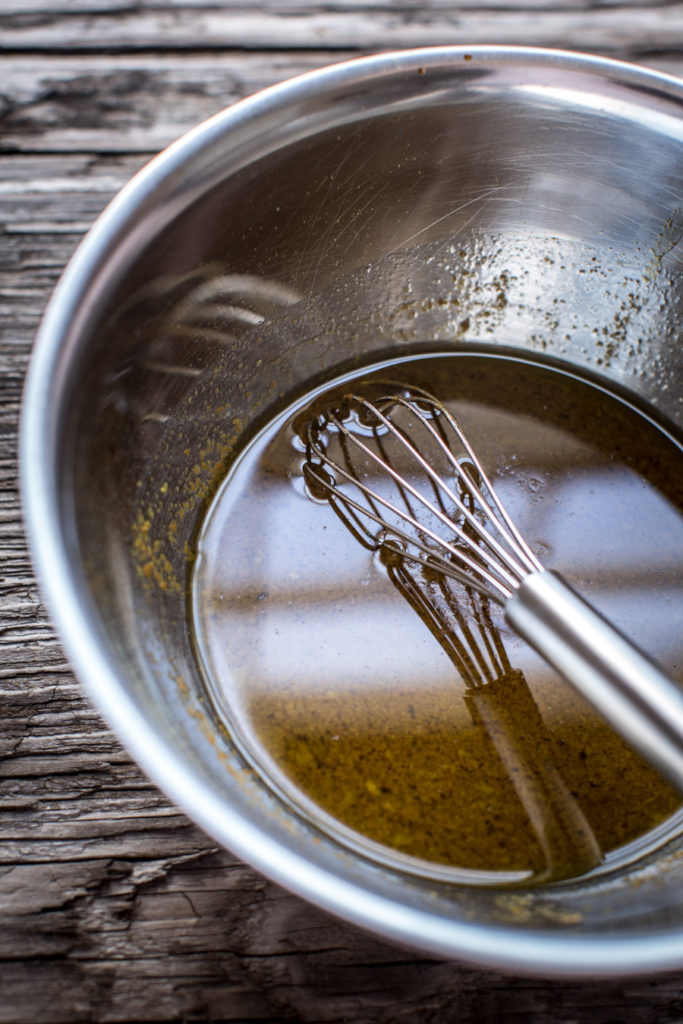 Spices and marinade in a large silver bowl with a whisk