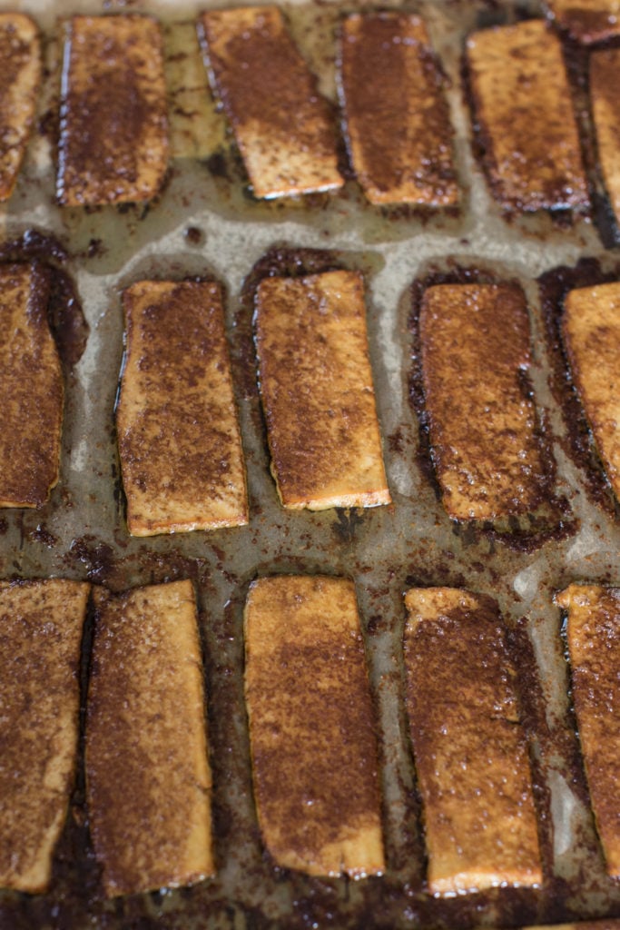 Seasoned tofu bacon before baking in the oven on parchment paper