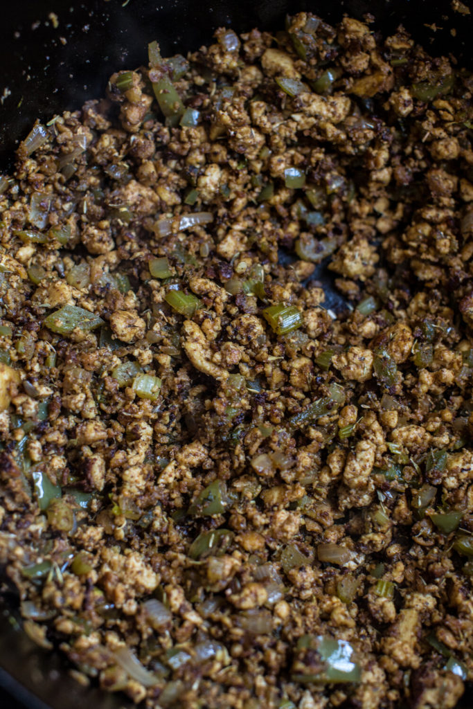 vegan tofu crumbles, onions, and celery in a cast iron skillet 