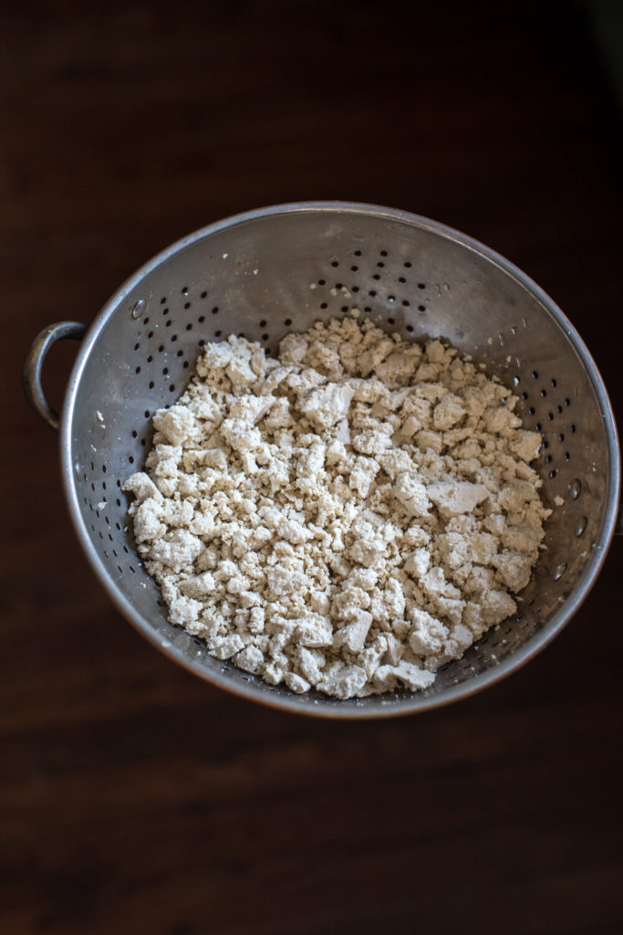 Tofu crumbles in a metal strainer