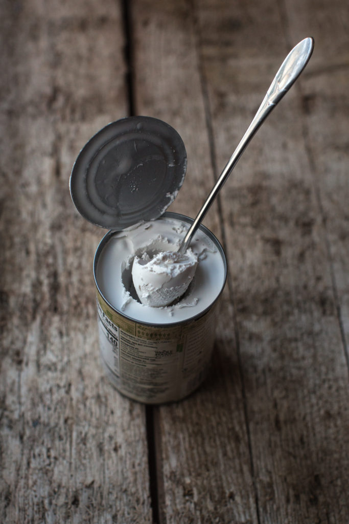 Open can of coconut cream with a spoonful coming out of the can