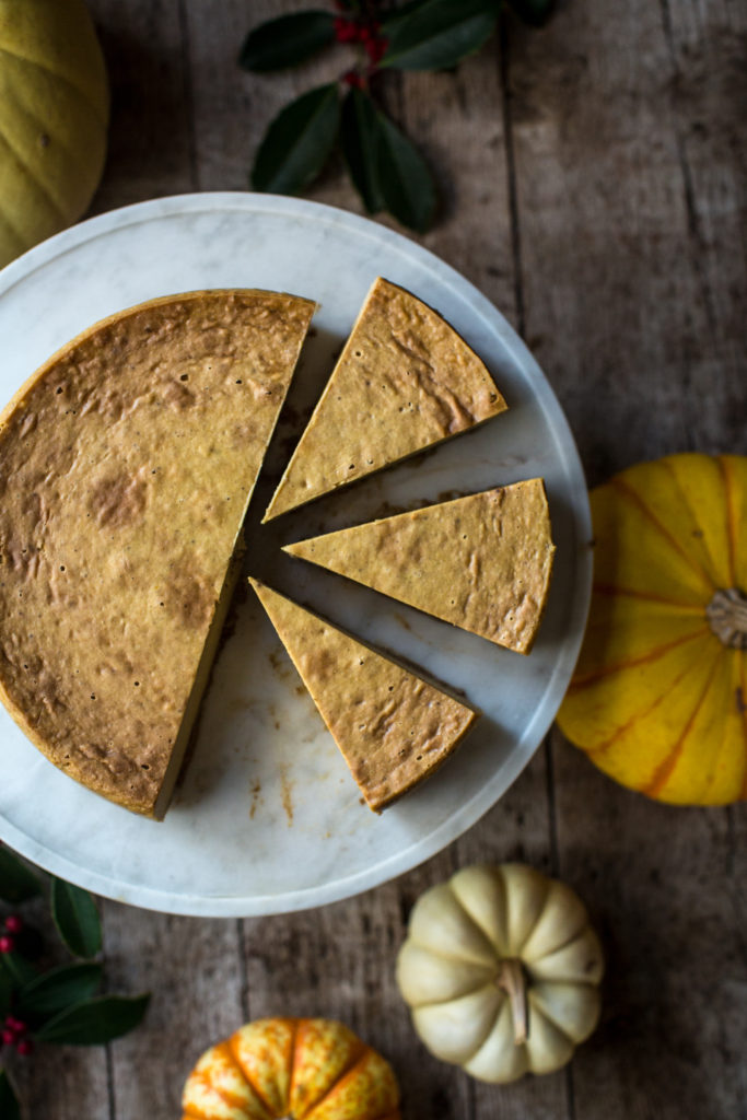 Three cut slices of pumpkin cheesecake on a serving tray next to the rest of the cheesecake
