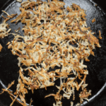 scattered hashbrowns on a cast iron skillet