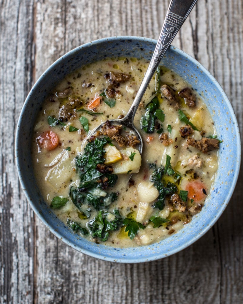 Blue bowl of Zuppa Toscana with a spoon in it