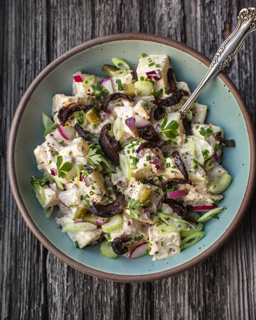creole potato salad in a bowl on wood