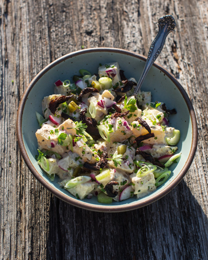 creole potato salad in a bowl on wood in the sun