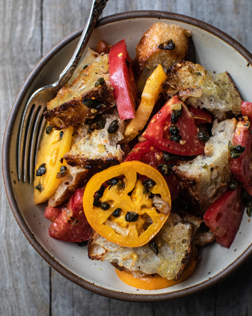 Bowl of fried caper panzanella with fork on the side