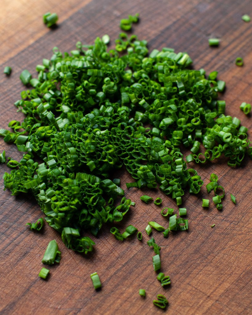 Freshly chopped chives on a wooden cutting board