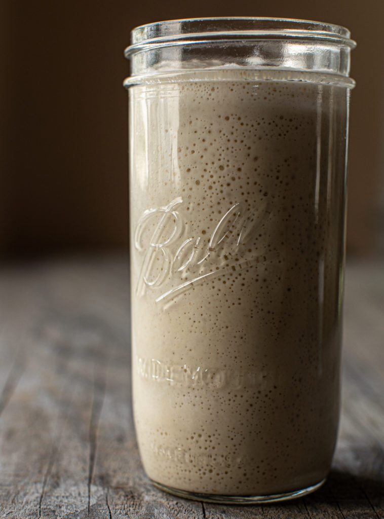 Side view of glass jar filled with sourdough starter