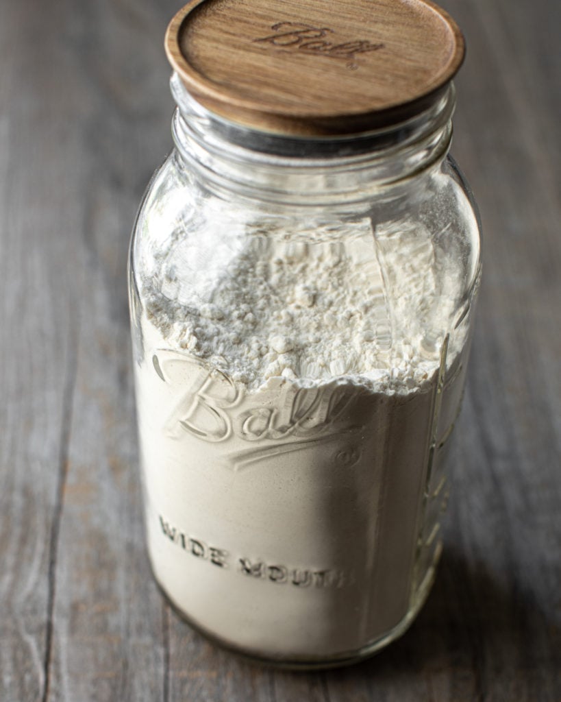 Glass jar with wooden lid filled with flour for recipe