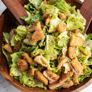a caeser salad topped with crispy vegan chicken