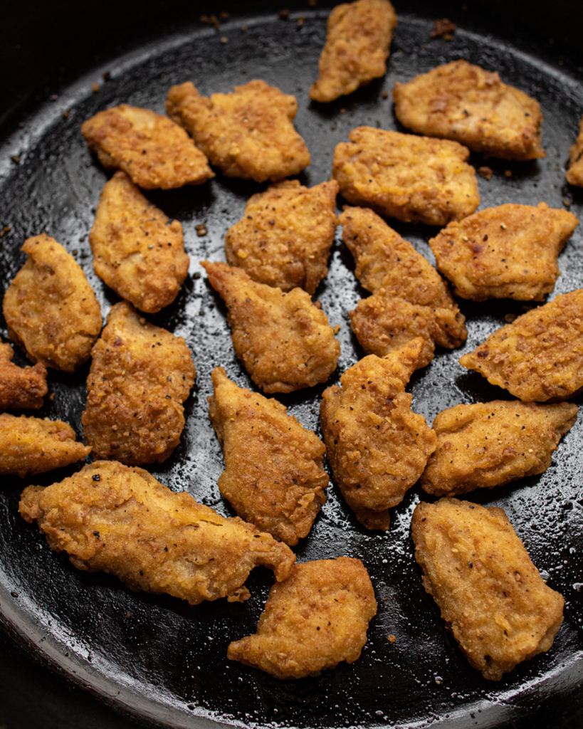Vegan chicken nuggets cooking in a cast iron skillet