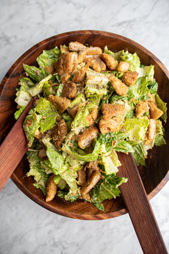 Wooden bowl filled with crispy chicken caesar salad