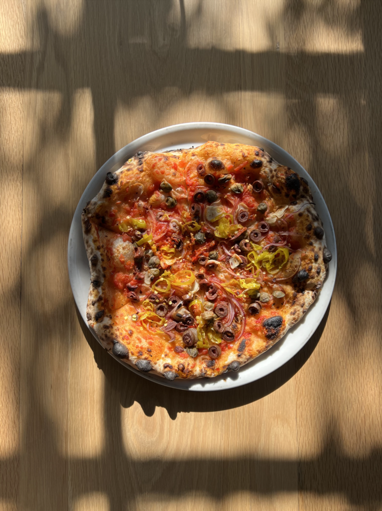 A pizza on a plate with vegetables on top