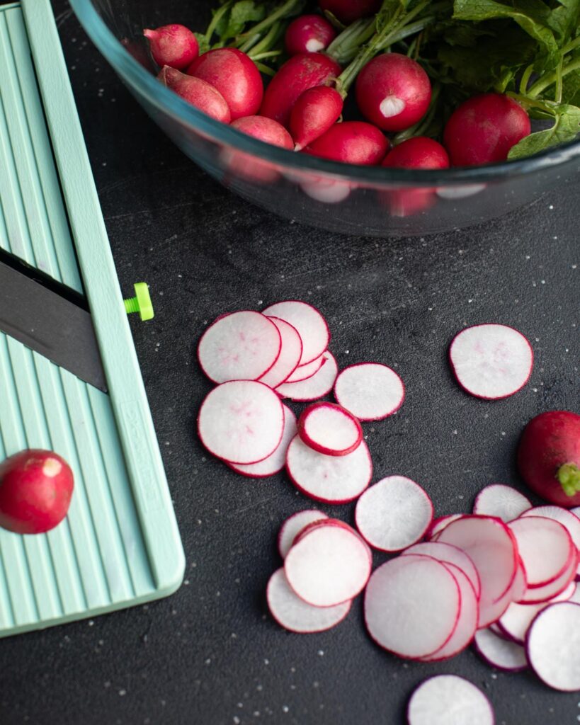 Sliced radishes on a mandolin