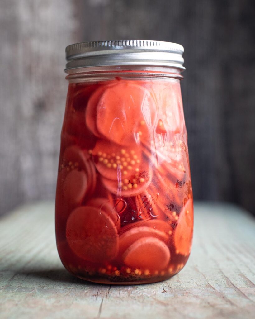 Glass jar with metal lid filled with sweet pickled radish