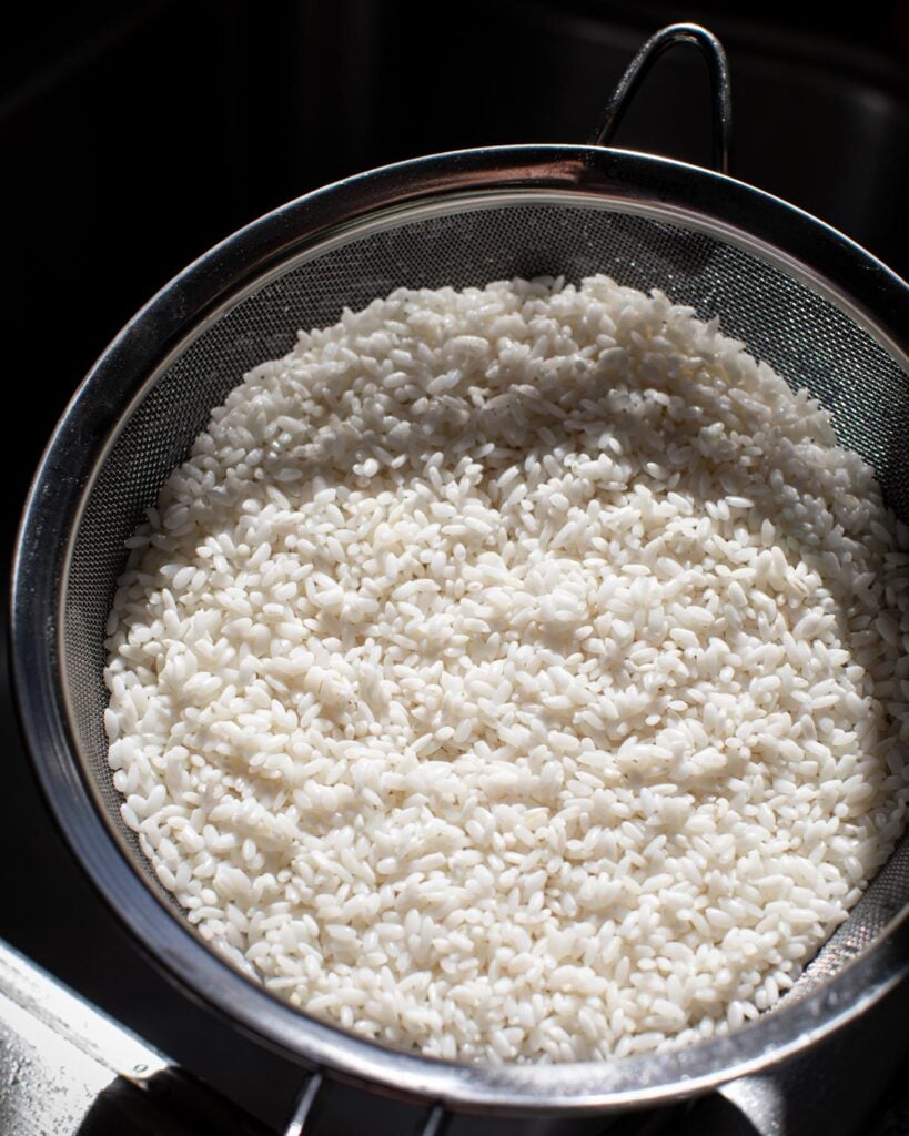Soaked rice draining in a metal strainer