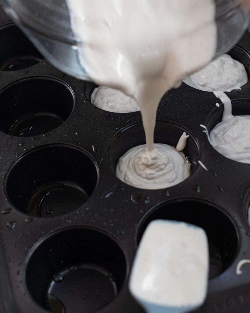 Dinner roll batter being poured into muffin pan