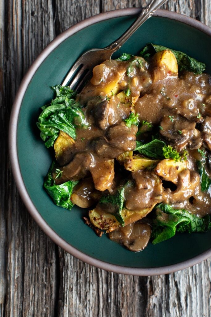 Mushroom gravy drizzled on potatoes and greens