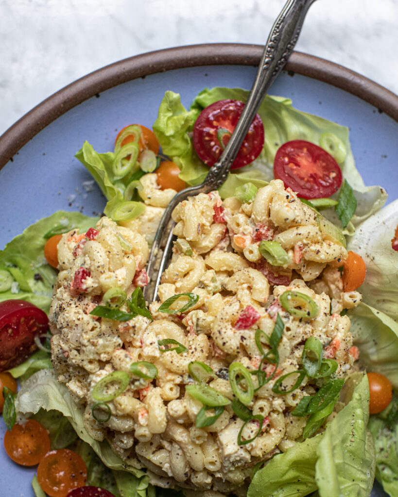 A mound of macaroni salad with a fork scooping a bite - a perfect high protein vegan meal