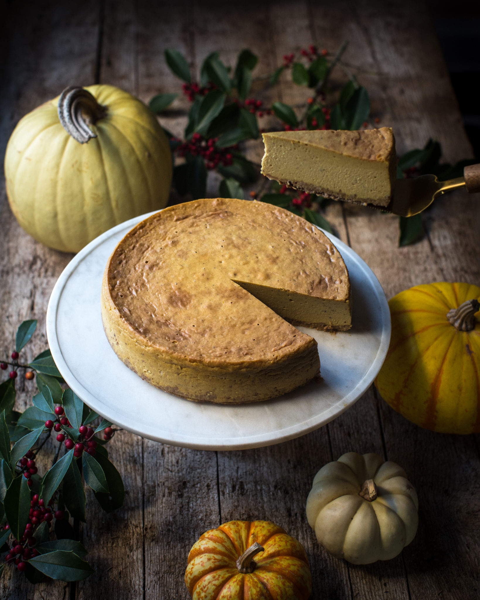Pumpkin cheesecake on a stand with a slice being removed - a vegan holiday recipe