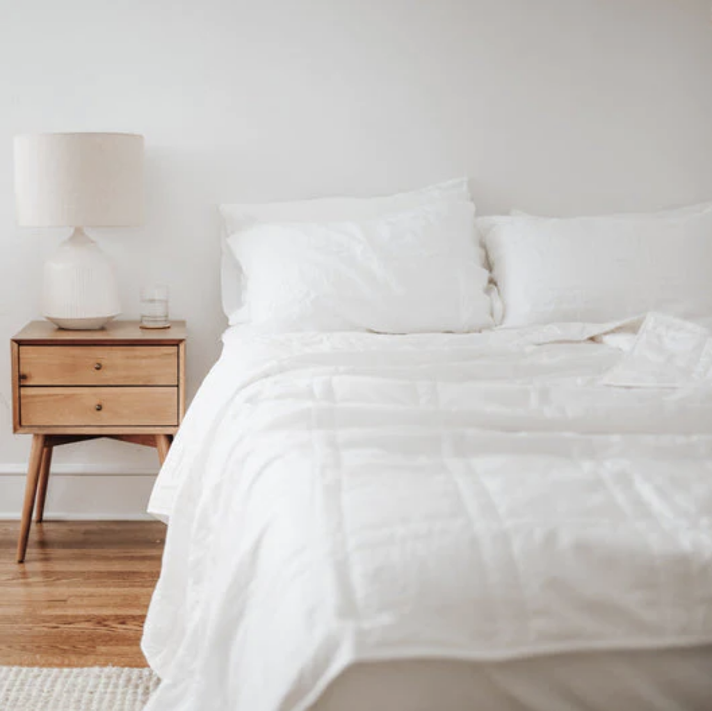bed with white linens and wooden side table