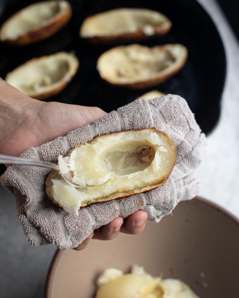 scooping out the flesh of baked potatoes