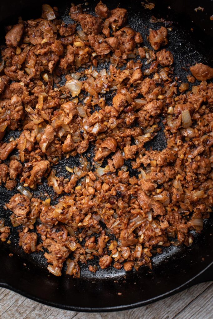 Crumbled plant-based sausage in skillet for epic lasagna
