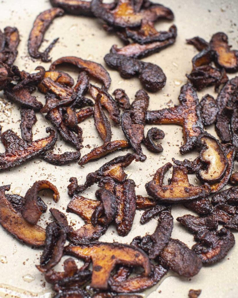 shiitake slices cooked in a skillet with marinade