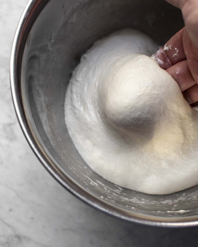 hand mixing the dough in a bowl