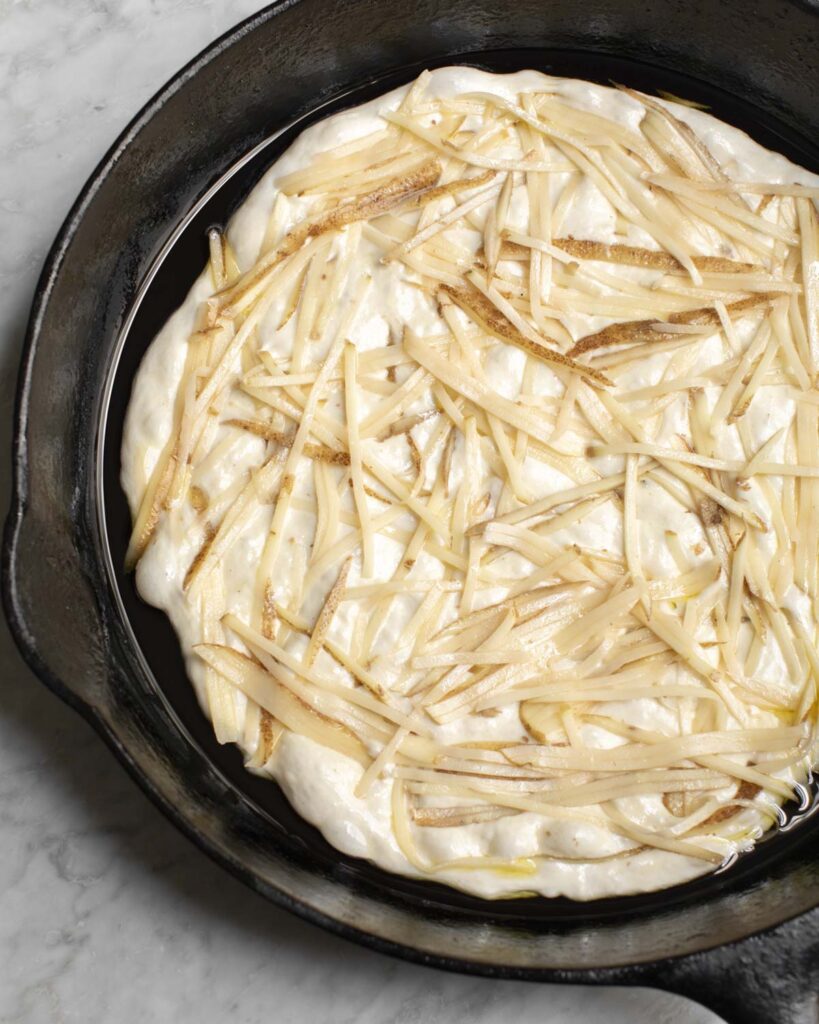 potato topping on the dough in a skillet
