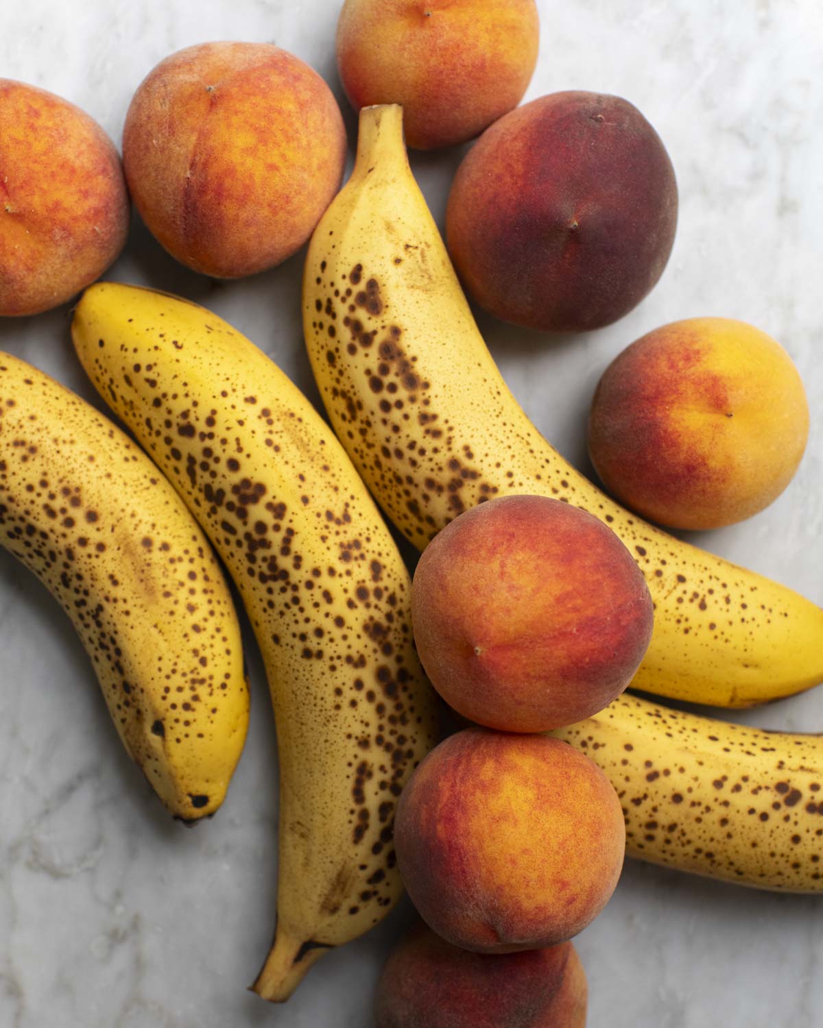 speckled bananas and peaches on a table