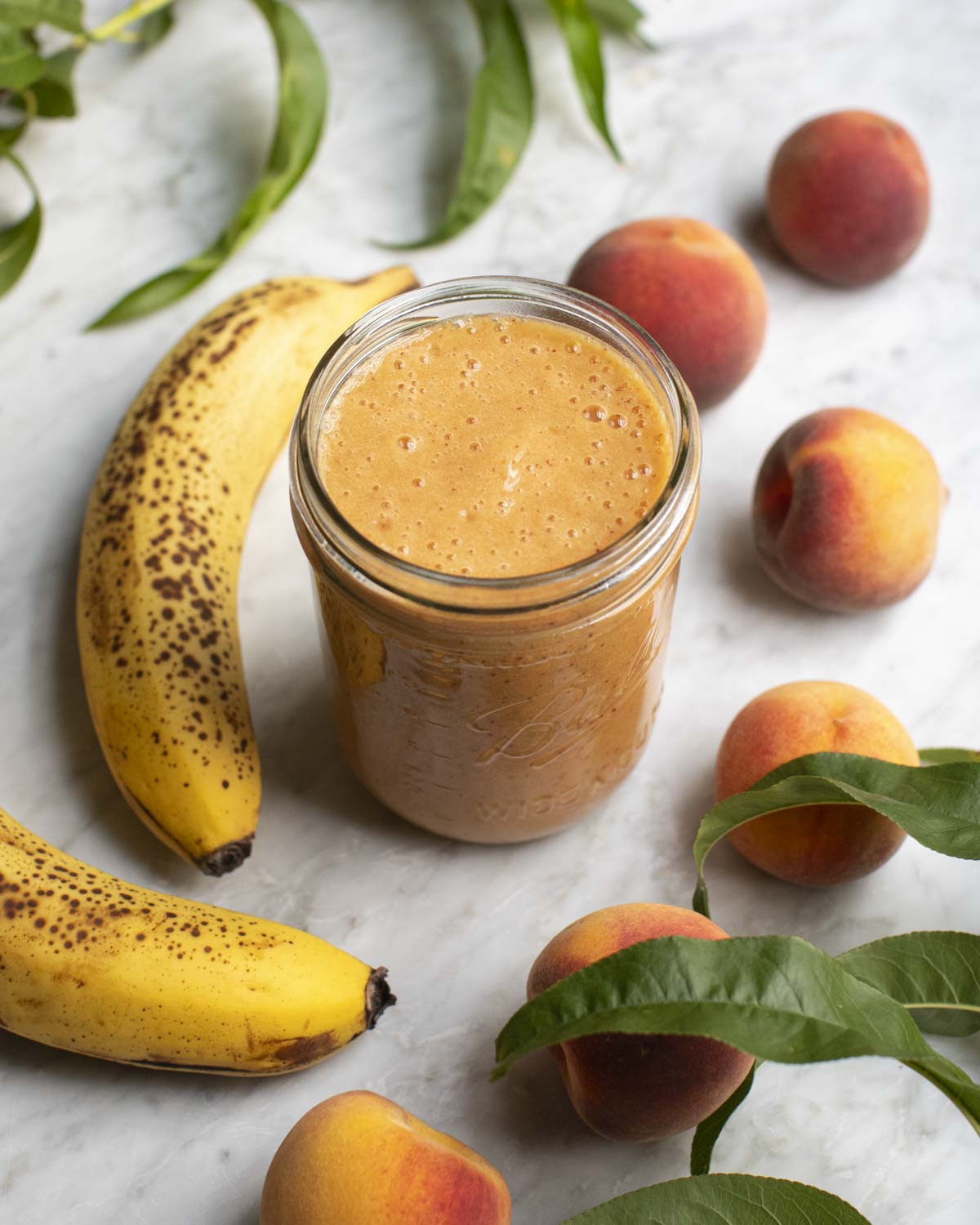 peach banana smoothie on a table with ingredients