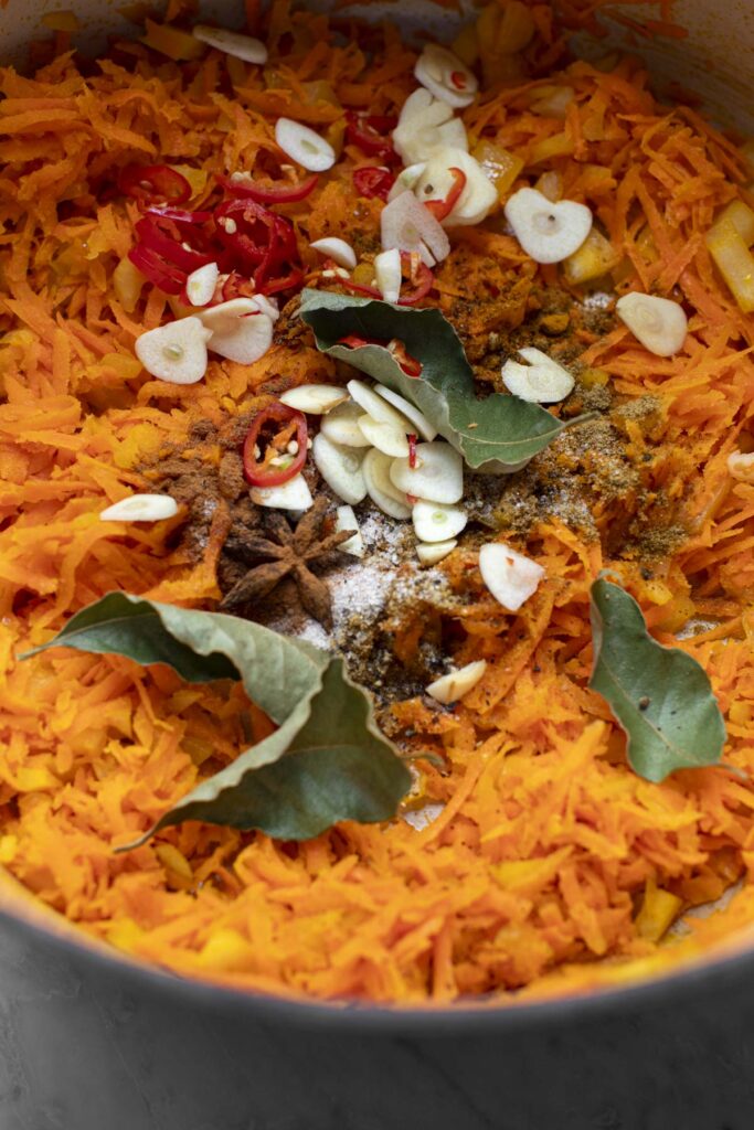 Shredded carrots, sliced garlic, and other ingredients in a pot