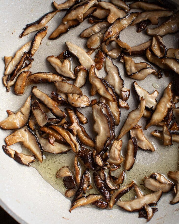 sliced shiitakes cooking in oil