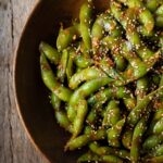garlic sesame edamame in a wooden bowl