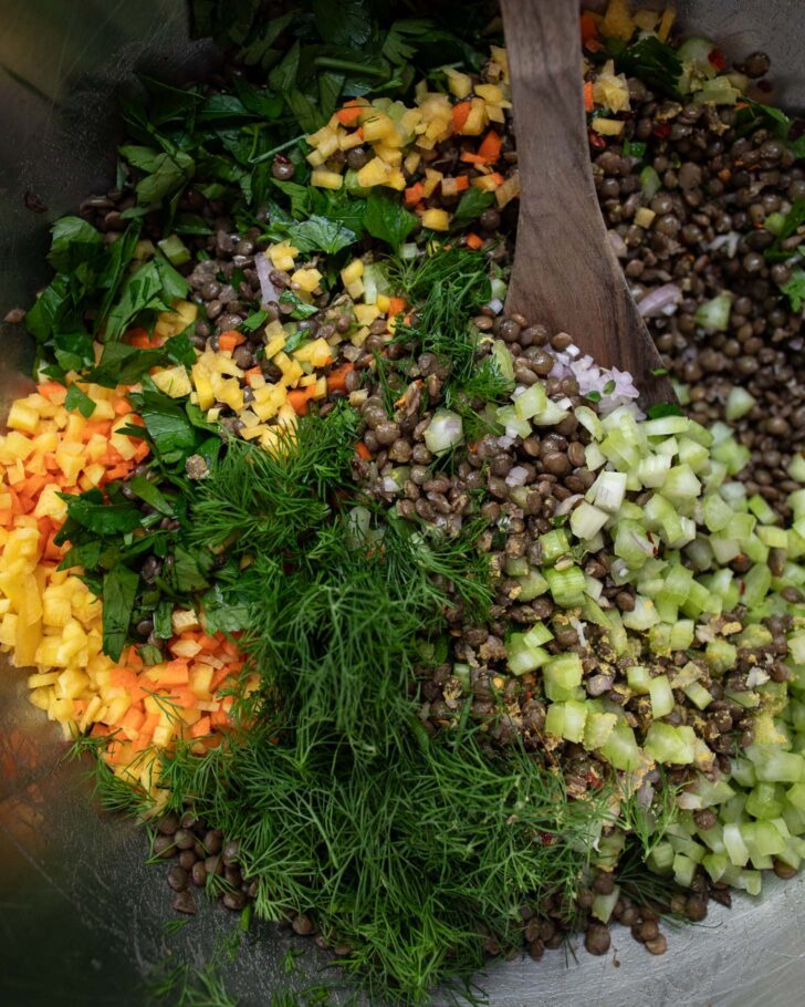 salad ingredients in a large bowl with a wooden spoon