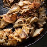 fried onions and potatoes in a skillet