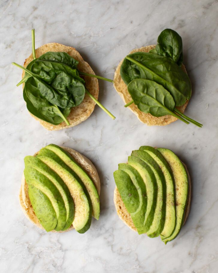toasted english muffins with spinach and avocado on top