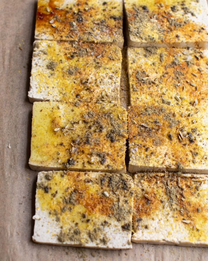 sliced tofu with seasonings on a baking sheet