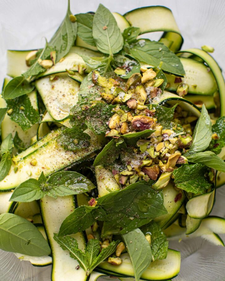 basil, mint, pistachios, and salt added to the salad in a large glass bowl